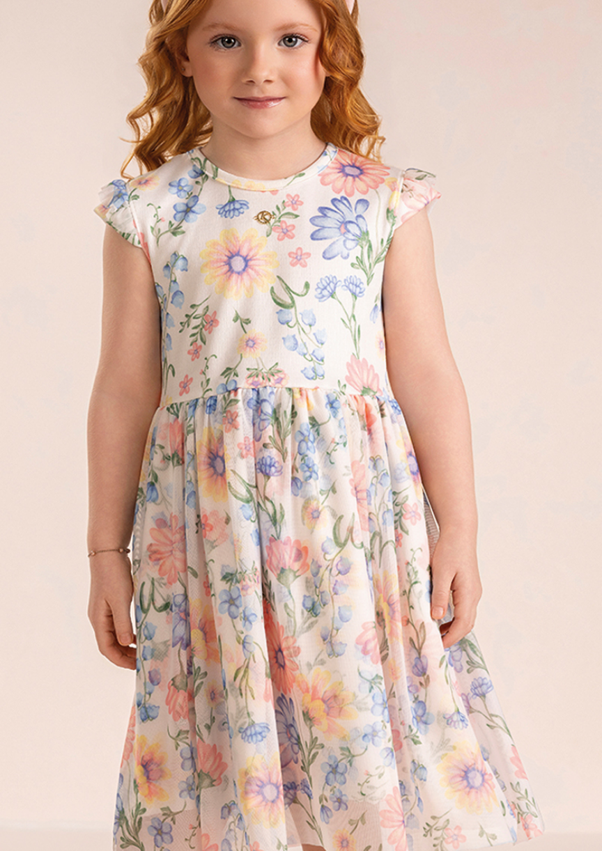 Garota vestindo vestido de verão floral com tule fresco e fluido para passeios e festas.