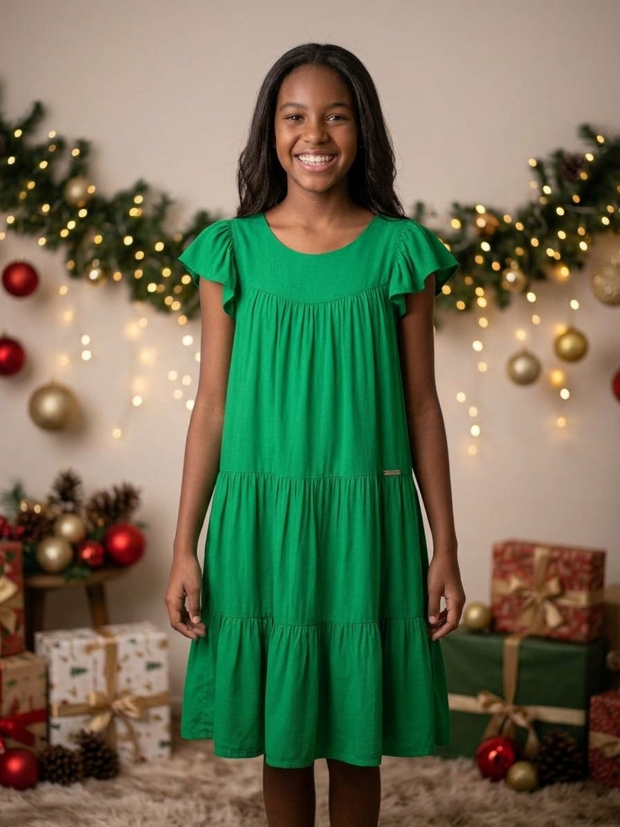 Adolescente sorrindo vestindo vestido juvenil verde soltinho em cenário natalino